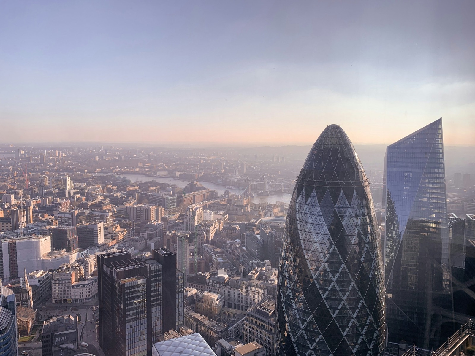London's skyline with the Gherkin and the River Thames in hazy evening light; illustrative stock photograph.